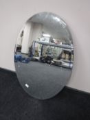 A large oval frameless bevelled mirror