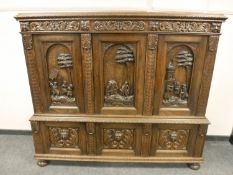A profusely carved continental triple door cabinet,