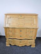 A blonde oak serpentine fronted bureau