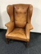 A twentieth century high backed button leather wing backed armchair