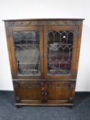 An oak leaded glass door bookcase fitted cupboards beneath