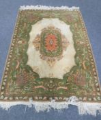 An Indian rug, with a central cream field enclosed by olive green borders,