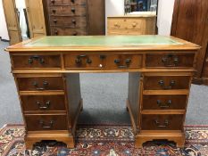 A reproduction yew wood pedestal desk with green leather insert,