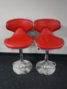A pair of red vinyl gas lift bar stools