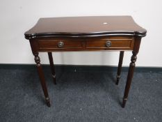 A reproduction mahogany foldover card table on reeded legs