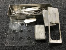 A stainless steel tray containing medical instruments together with a small glass vessel,