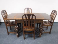 An early 20th century oak pull out table on carved legs with four matching chairs