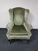 A mahogany wing back armchair in green dralon on claw and ball feet