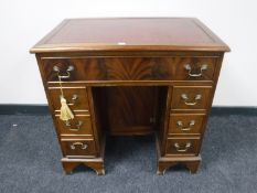 A mahogany Regency style kneehole desk with inset red leather panel