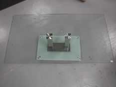 A contemporary rectangular glass topped coffee table on a glass and metal base