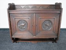 An Edwardian oak wall cabinet with carved panel doors