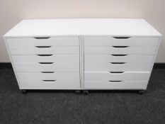 A pair of white six-drawer chests on wheels