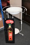 A metal framed wash basin and an enamel Bev advertising sign