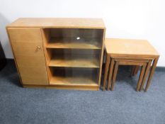 A nest of three teak tables and a teak sliding door bookcase