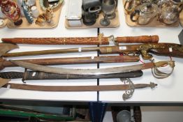 A collection of antique style weapons including Indian sabre, double headed axe, musket etc.