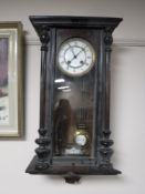 An Edwardian stained beech wall clock with enamelled dial