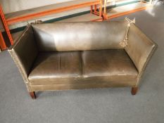 A brown studded leather drop end two seater settee