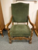 A carved oak armchair upholstered in green fabric