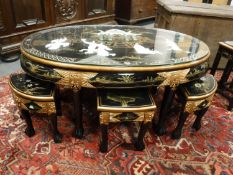 A Japanese lacquered large oval coffee table, with nest stools beneath,