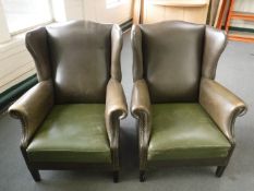 A pair of studded brown leather wingback armchairs