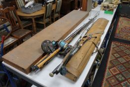 A large collection of fishing rods, reels, wooden storage case containing rods,