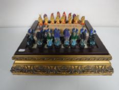 A chess board on gilt base with dragon pieces together with a boxed set of vintage dominoes