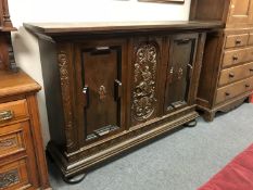 A heavily carved oak triple door sideboard on bun feet