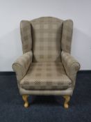A wing armchair in gold fabric