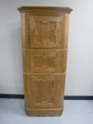 A blonde oak triple door corner cupboard