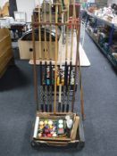 A snooker cue rack and six two piece pool cues, another cue, a cue rest, box of pool balls,