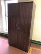 A double door upright archive cabinet in a mahogany finish