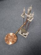A four piece brass handled companion set on stand and a copper bed warmer