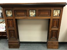 A late Victorian oak fire surround inset with ceramic panels by Cottier & Co., width 167 cm.