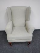 A wingback armchair in a beige fabric