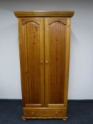 A pine double door wardrobe fitted with a drawer