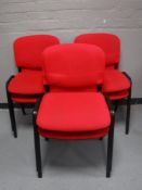 A set of six metal framed stacking chairs upholstered in red fabric