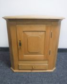 An antique style light oak corner cabinet