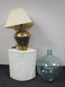 A glass carboy together with a loom linen box and a brass table lamp with shade