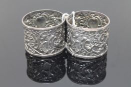An ornate pair of silver napkin rings with putti playing drums (2)