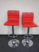 A pair of red leather gas lift bar stools