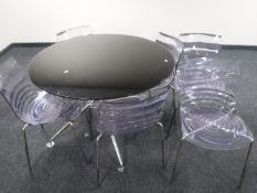 A contemporary glass topped circular dining table and six Perspex chairs