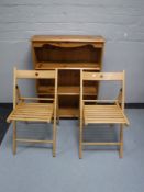 A set of pine open bookshelves together with two folding kitchen chairs