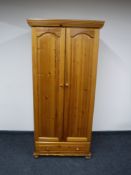 A pine double door wardrobe fitted with a drawer