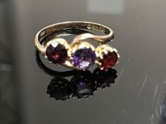 A 9ct gold amethyst and garnet three stone crossover ring,