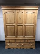A pine triple door wardrobe fitted with five drawers,
