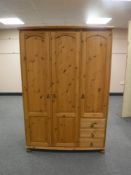 A pine triple door wardrobe fitted three drawers