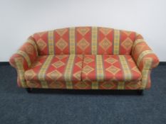 A settee upholstered in multi coloured fabric