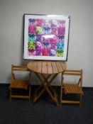 A folding child's patio table and two chairs and a print