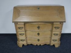 An early 20th century continental oak serpentine fronted bureau