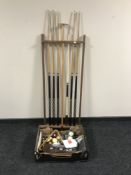 A snooker cue rack containing six two-piece cues and a rest, together with a box of pool balls,
